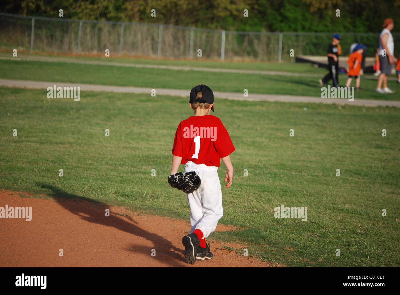 Cute little league baseball player walking on field from behind. Stock Photo