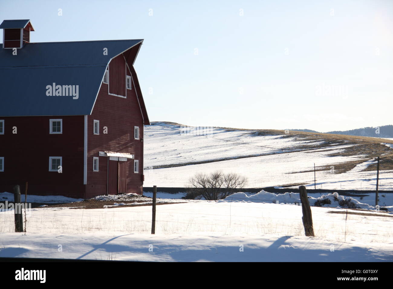 a red barn with a wood fence sits in a snowy field Stock Photo - Alamy
