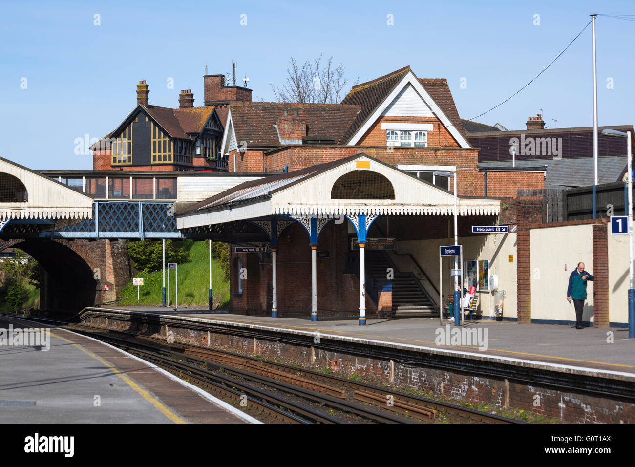Man standing on platform looking at watch at Branksome train station, Dorset, UK in May Stock Photo