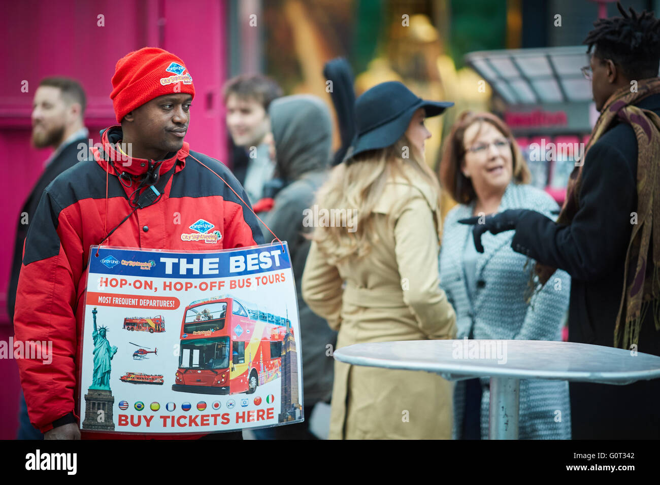 New York times Square   red uniform selling hop on off bus tickets grayling representative coach tours seller with sign stopping Stock Photo