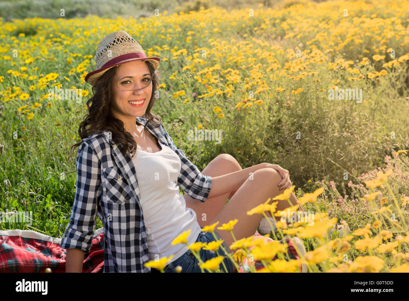 beautiful woman laughing sitting on the grass and daisies field n the field Stock Photo