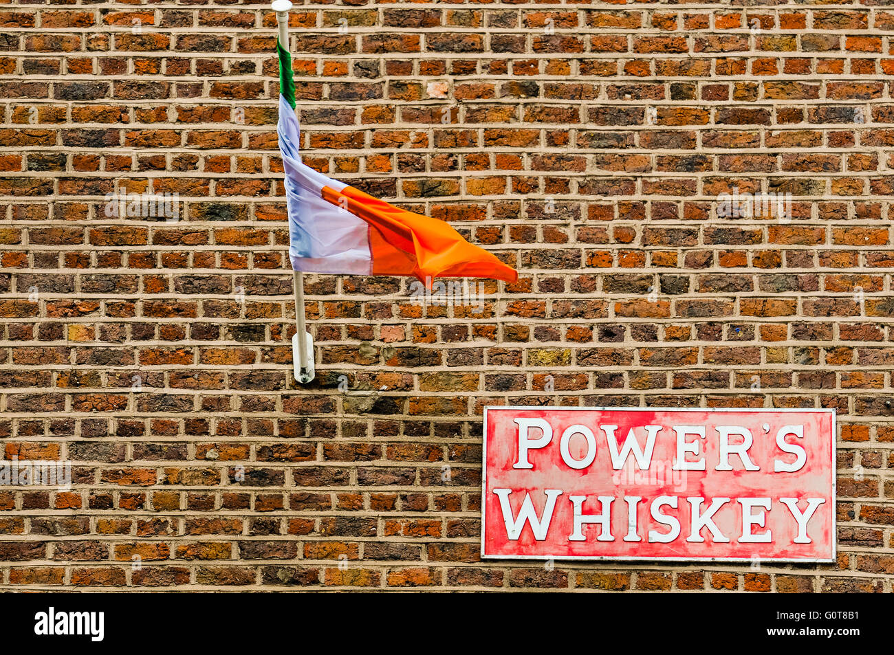 An Irish Tricolour and a sign for Power's Whiskey on a wall of an Irish pub in Dublin. Stock Photo