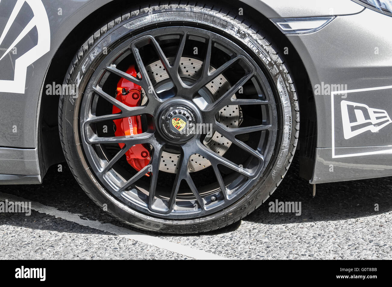Red disc brake calipers on the front wheel of a Porsche Targa 4S. Stock Photo