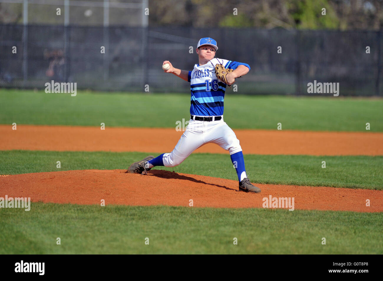 Right-handed pitcher delivering a pitch to a waiting hitter during a high school baseball game. Stock Photo