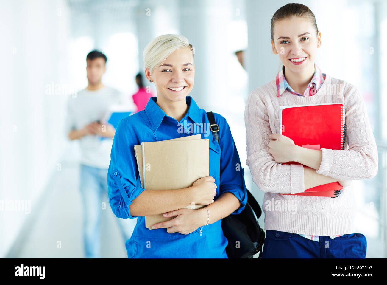 Two pretty students with books looking at camera Stock Photo - Alamy