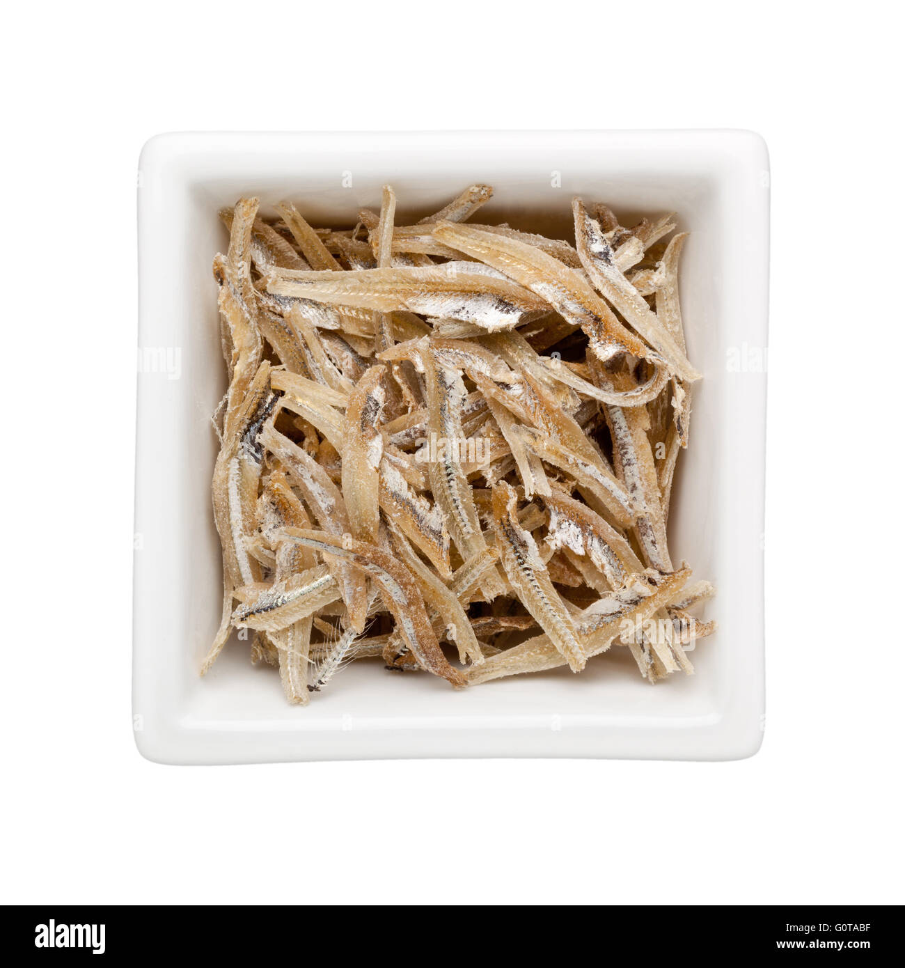 Dried anchovies in a square bowl isolated on white background Stock Photo