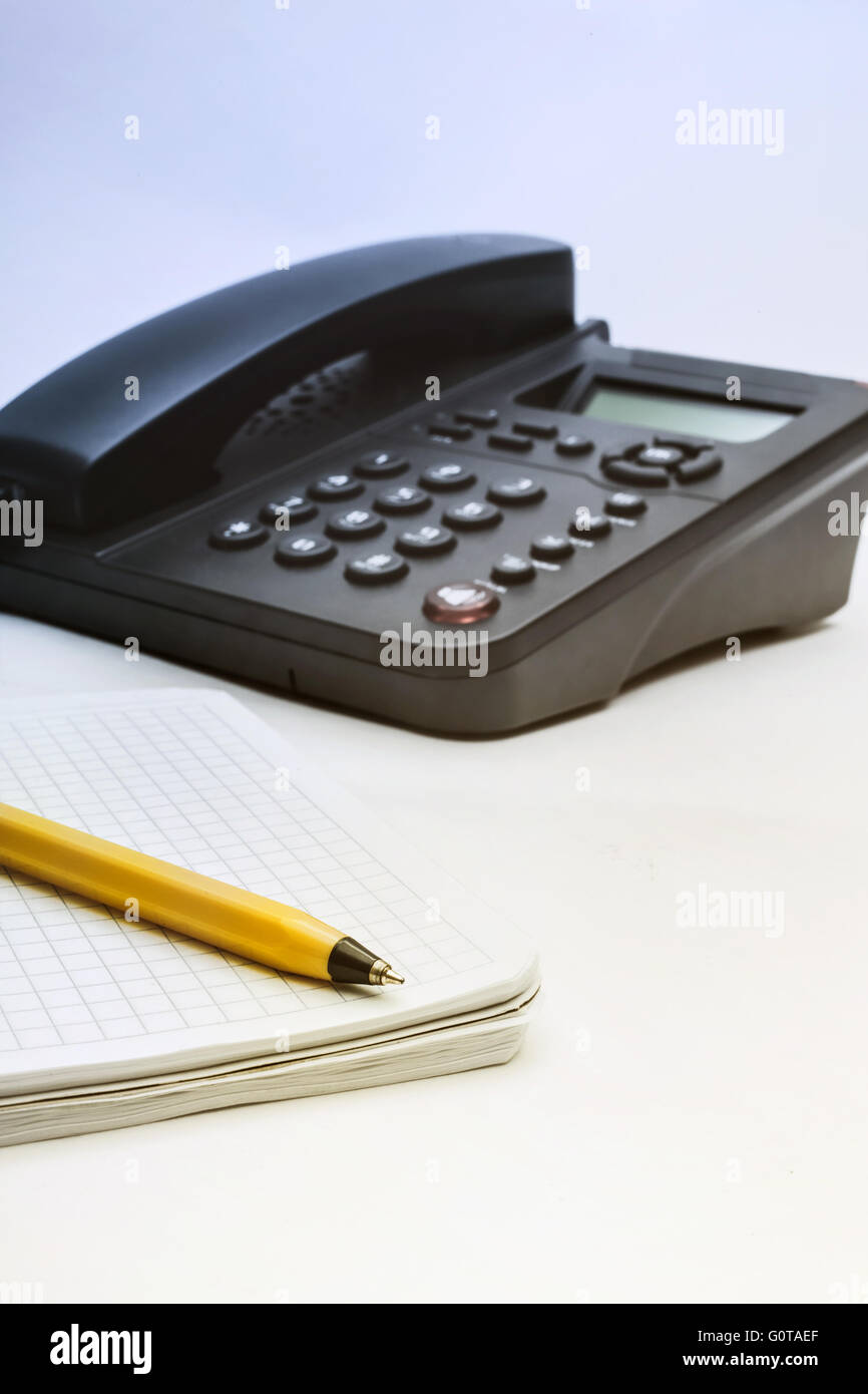 Black IP phone, notebook and pen on white background Stock Photo
