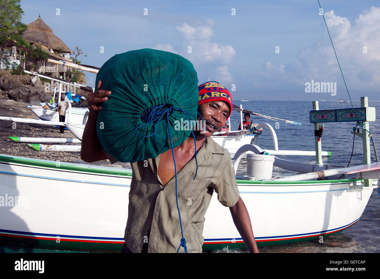 Man unloading fish Selang Amed East coast Bali Indonesia Stock Photo