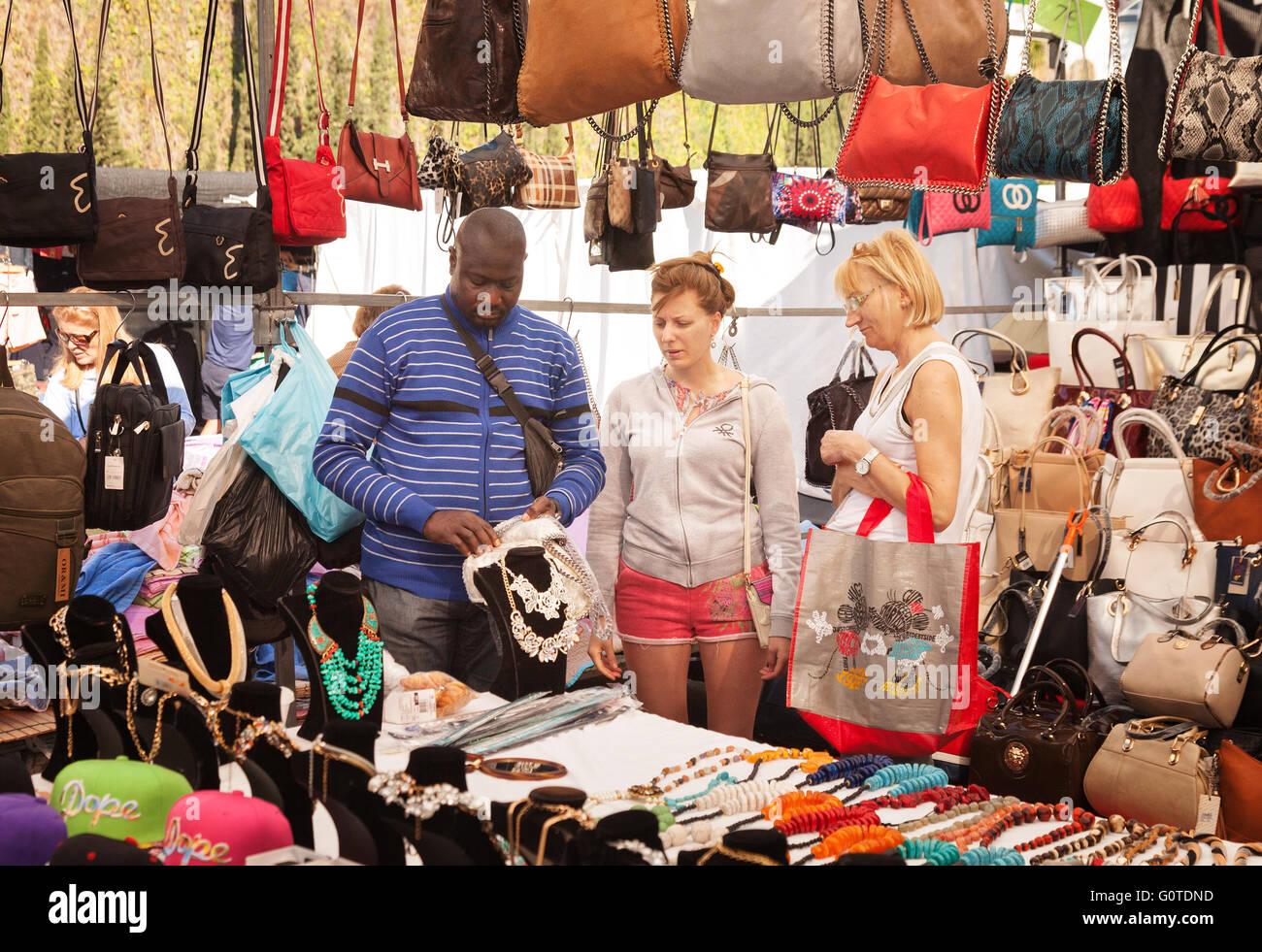 Woman buying a handbag from a market stall, Marbella outdoor market, Marbella, Andalusia Spain Europe Stock Photo