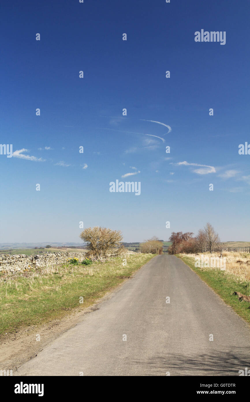 Swirling contrails above a rural road Stock Photo