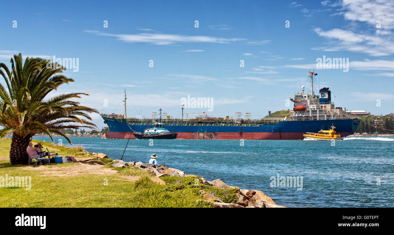 A tanker is guided out to sea by the harbour pilot and a tug boat. Stock Photo