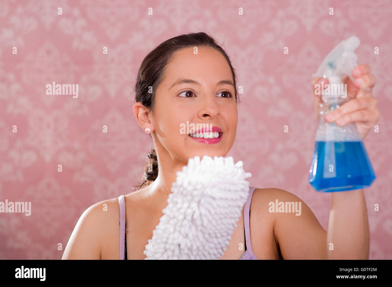 woman holding spray bottle of blue liquid and white fluffy