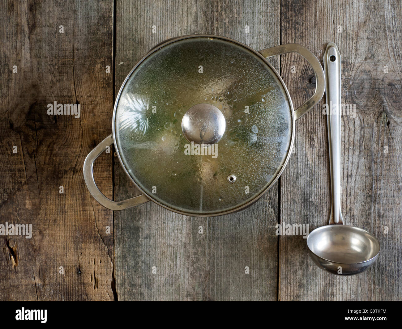 Saucepan of chicken soup with ladle on wooden table Stock Photo