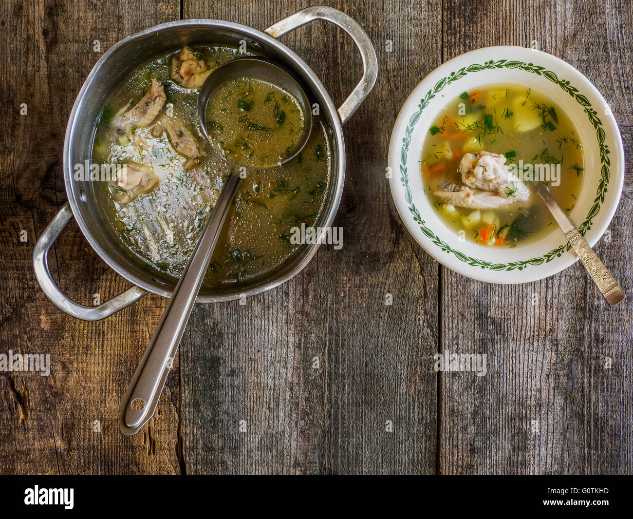 Saucepan and bowl of chicken soup on wooden table Stock Photo