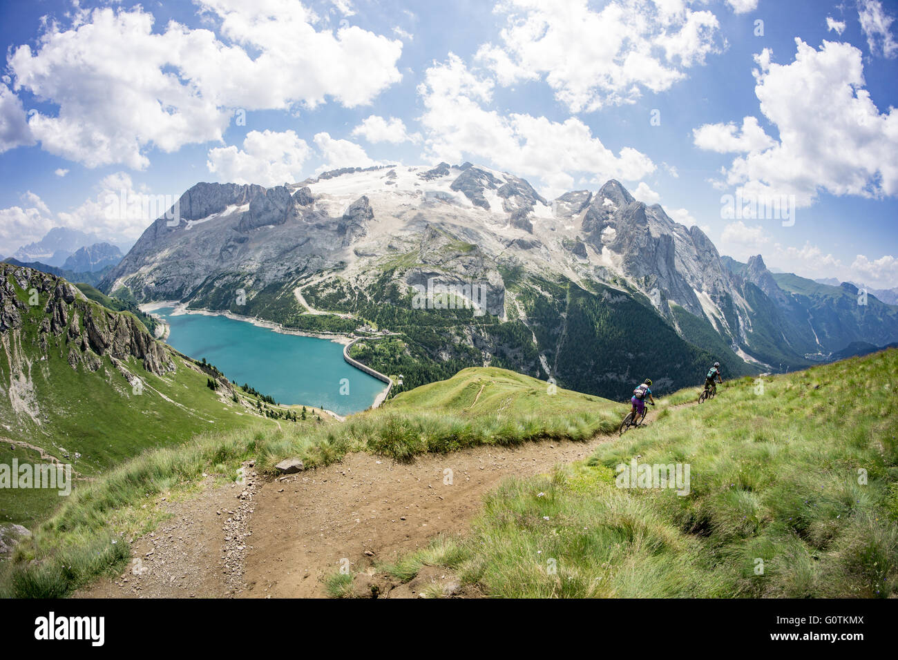 Man and woman riding mountain bikes along trail, Dolomites, Italy Stock Photo