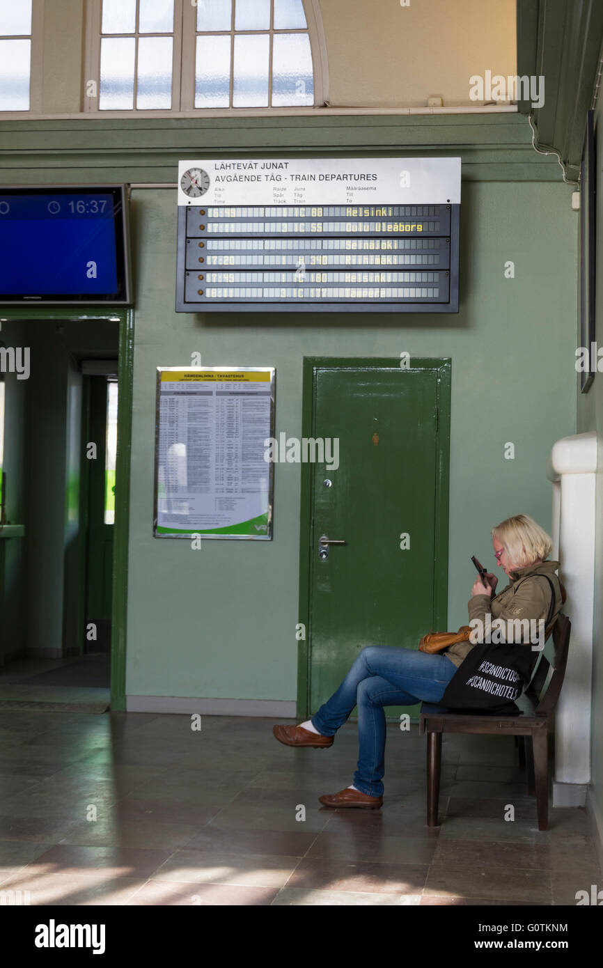 Woman sitting in Hämeenlinna railway station waiting room in Hämeenlinna Finland Stock Photo