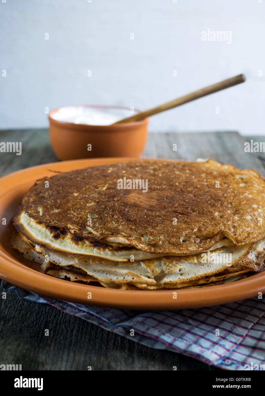 Stack of crepe pancakes on plate with pot of cream Stock Photo