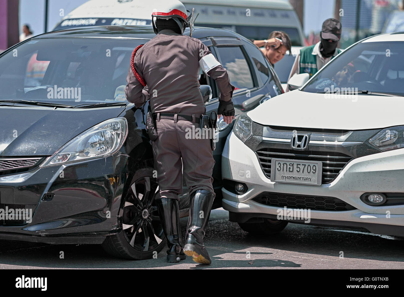 Thailand police officer attending a road accident involving the collision of two vehicles. Thailand S. E. Asia Stock Photo