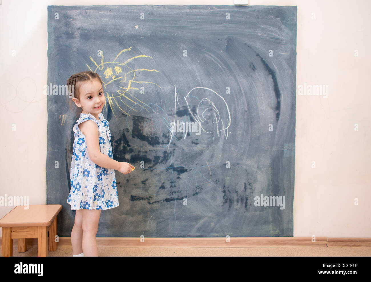 Full length cute little girl standing near blackboard Stock Photo