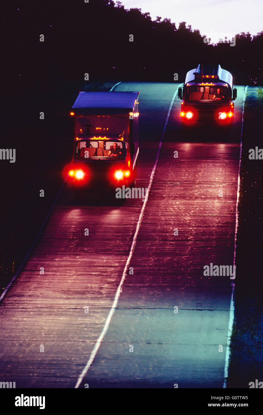 Trucks traveling on road at night Stock Photo