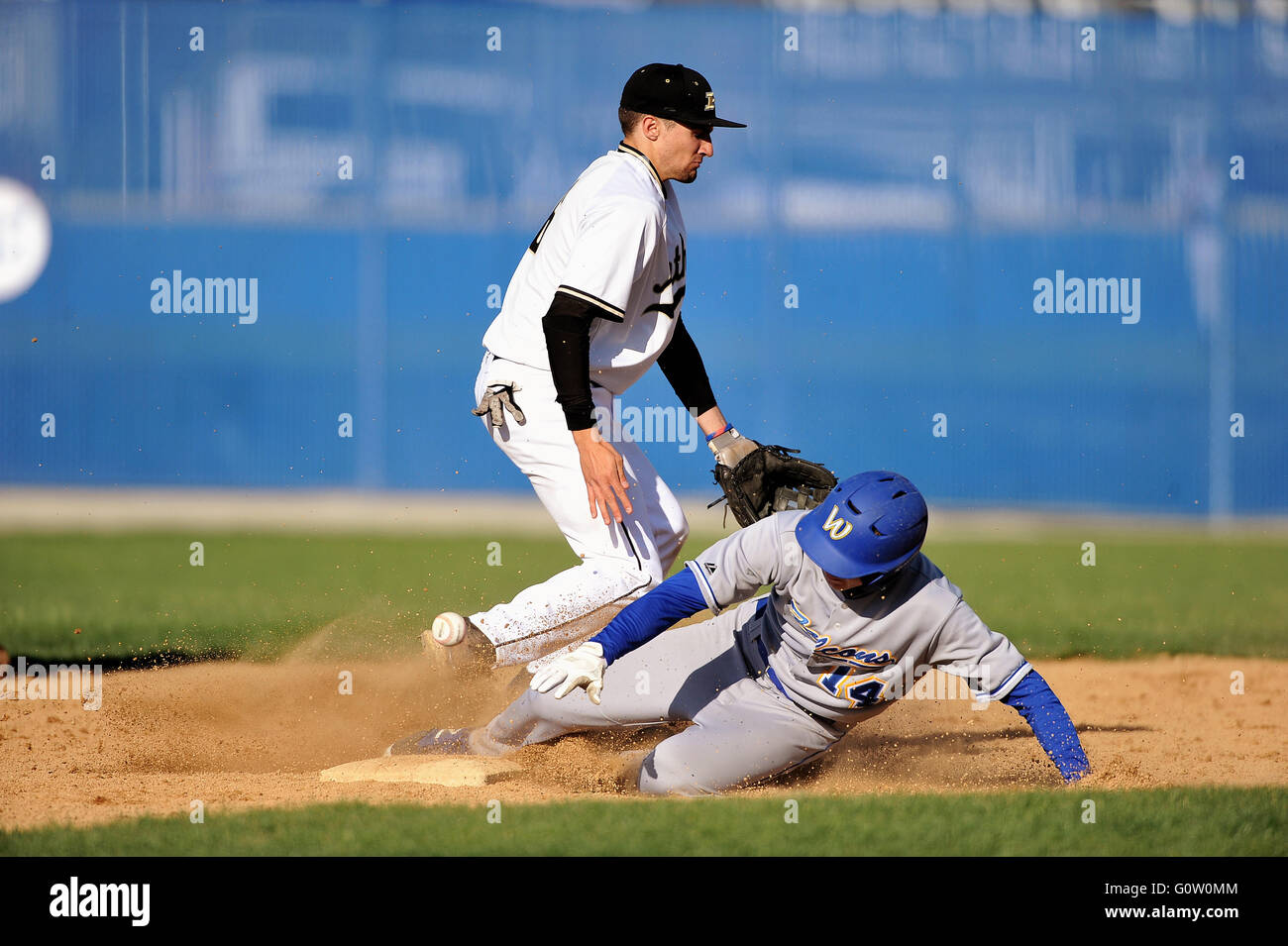 High school runner sliding in safely with a steal of second as a shortstop can only knock down the throw from his catcher. USA. Stock Photo