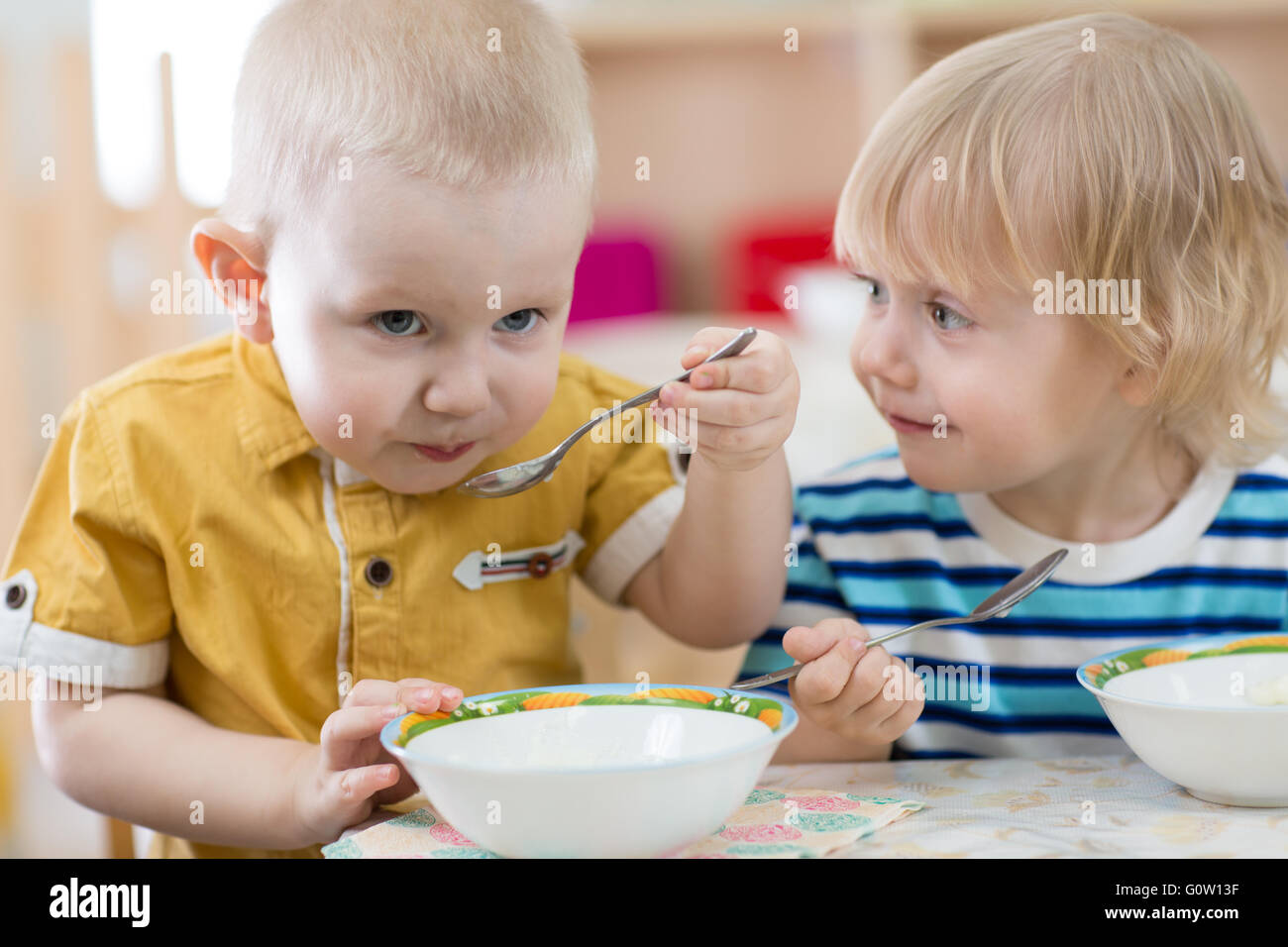 Funny smiling little kid eating in kindergarten Stock Photo