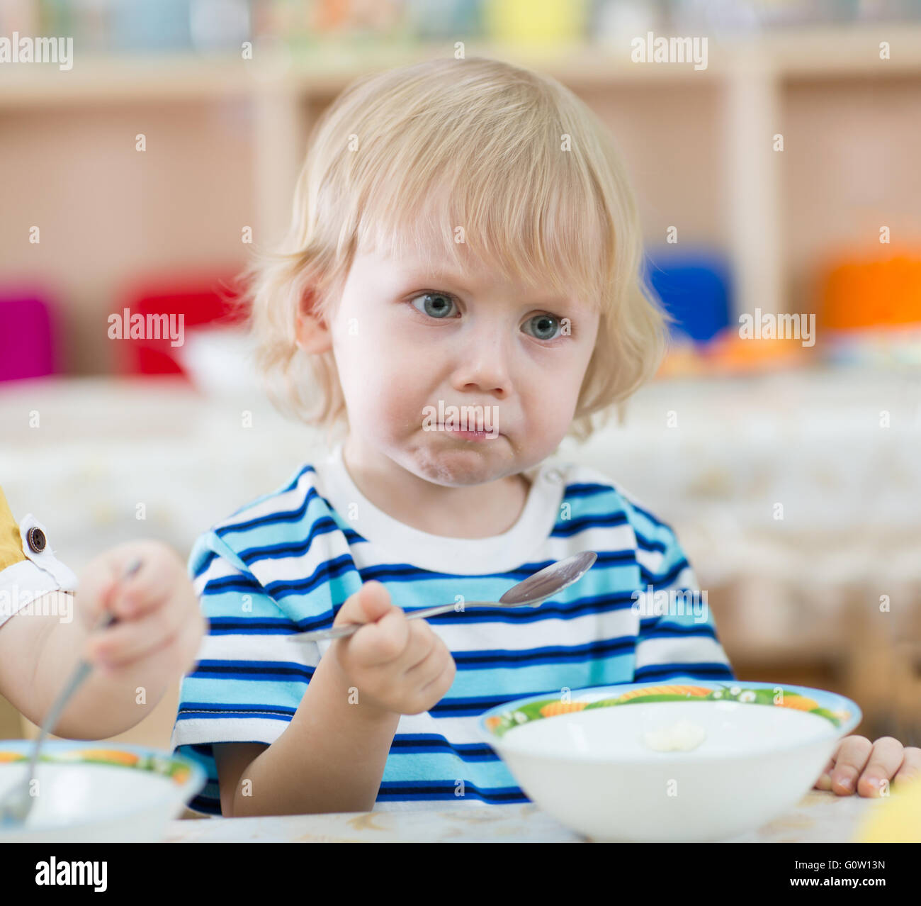 serious kid eating from plates in kindergarten Stock Photo