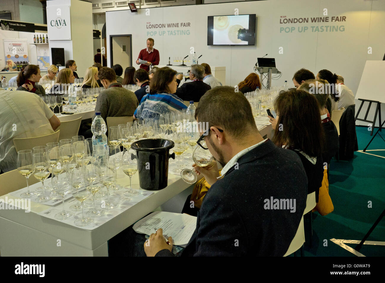 Exhibitors and traders taste wine at the London International Wine Fair at the Olympia Exhibition centre. London, UK Stock Photo