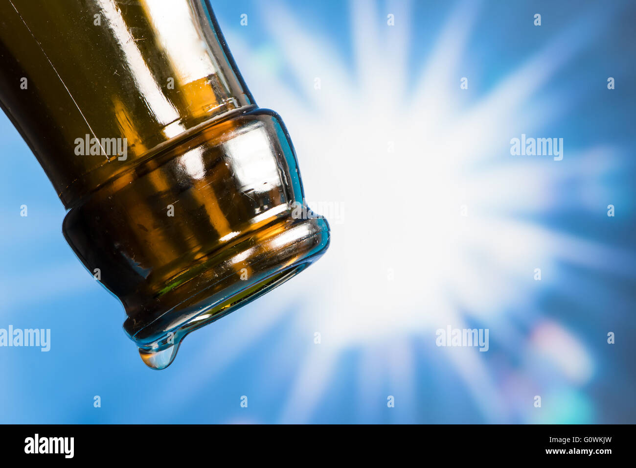 Last drop of an empty beer bottle with the sun in the background Stock Photo