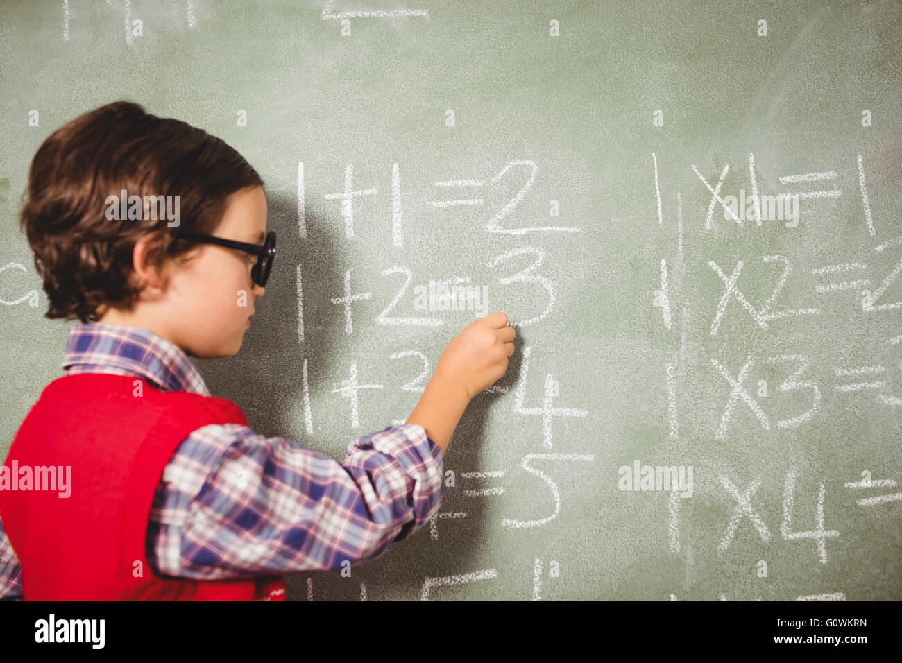 Boy writing with chalk on blackboard Stock Photo