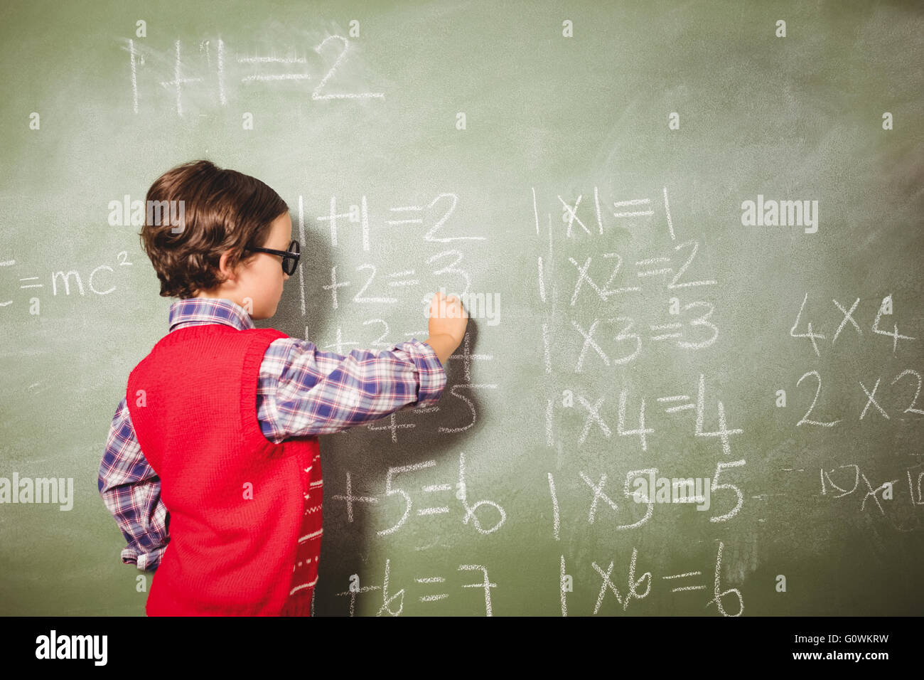 Boy writing with chalk on blackboard Stock Photo
