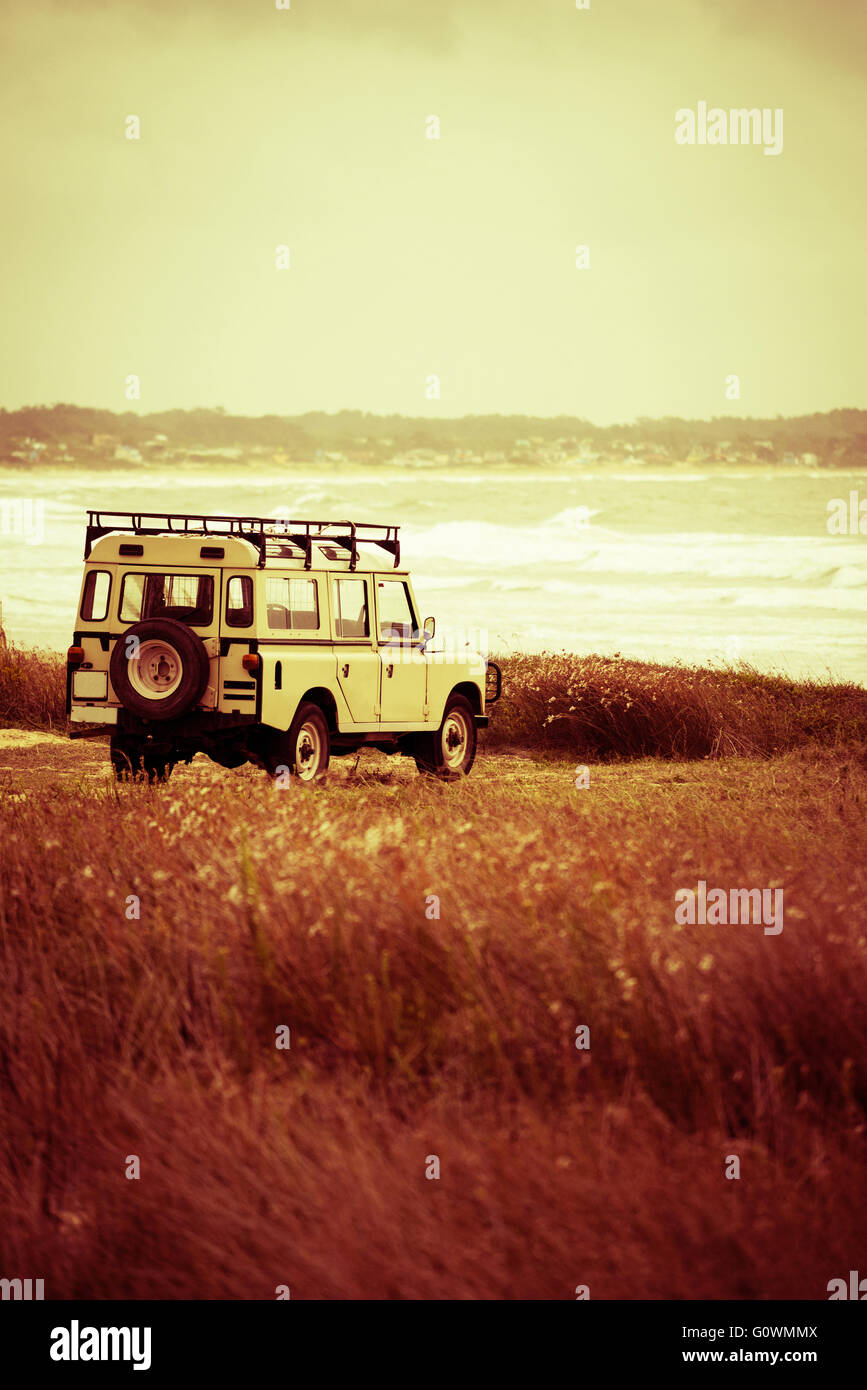 Vintage car on wild beach landscape view, peaceful summer vacation trip adventure. Stock Photo