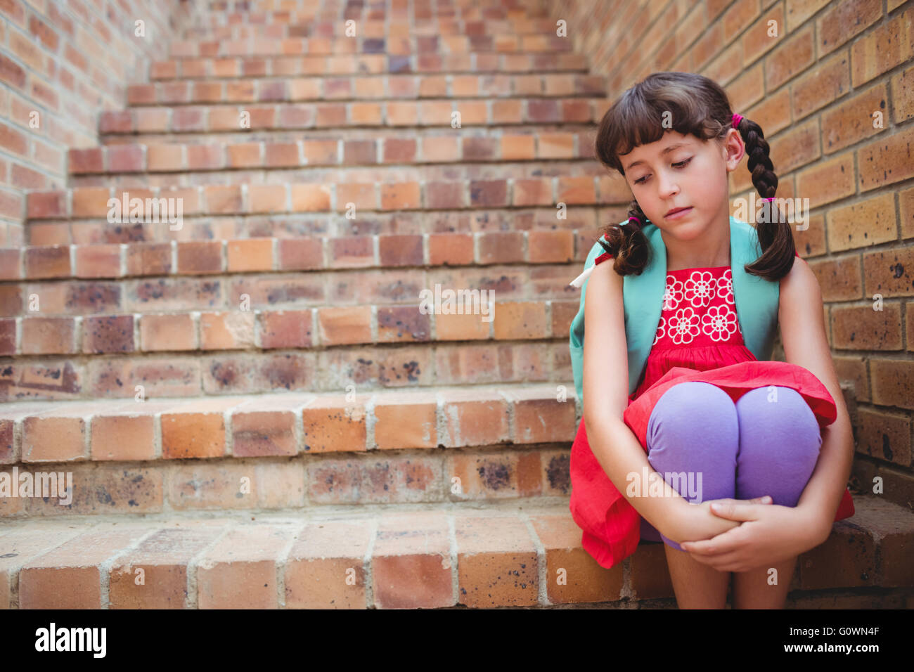 Sad schoolgirl siting in stairs Stock Photo