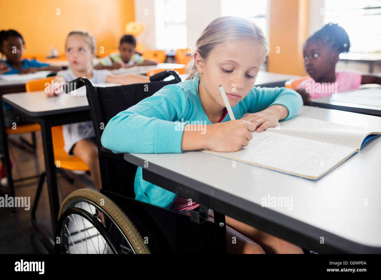 Portrait of a cute pupil in wheel chair working at desk Stock Photo - Alamy