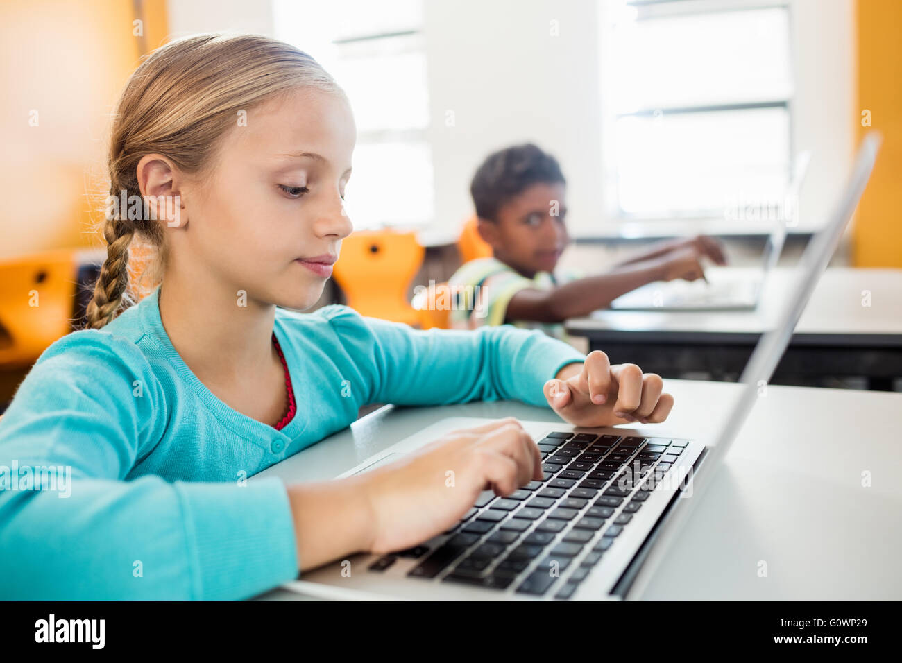 Side view of little girl using laptop in classroom Stock Photo