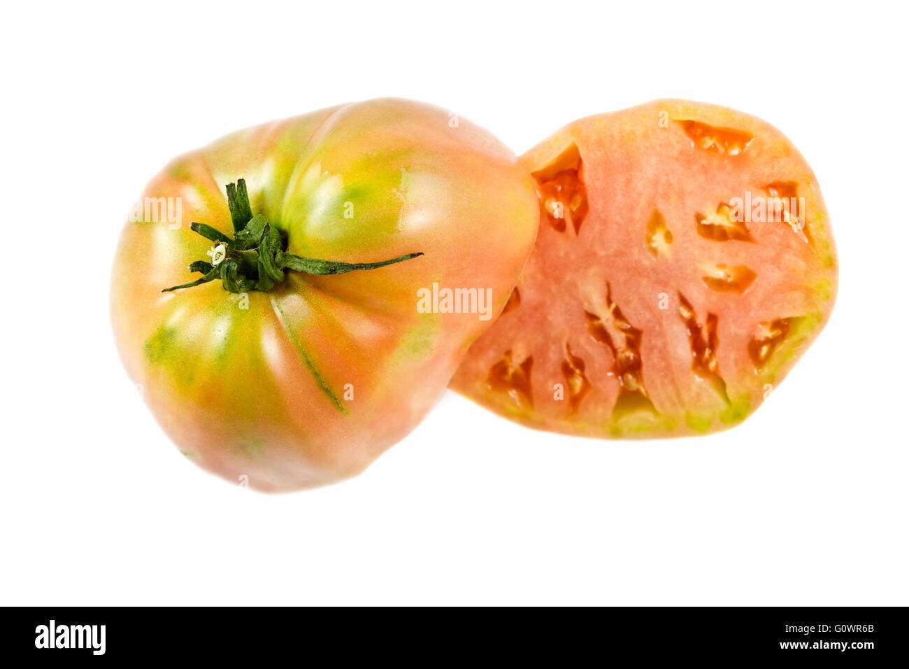Near ripe ox heart tomato, Solanum lycopersicum, showing many small seed compartments, called locules, and a nice pink flesh. Stock Photo