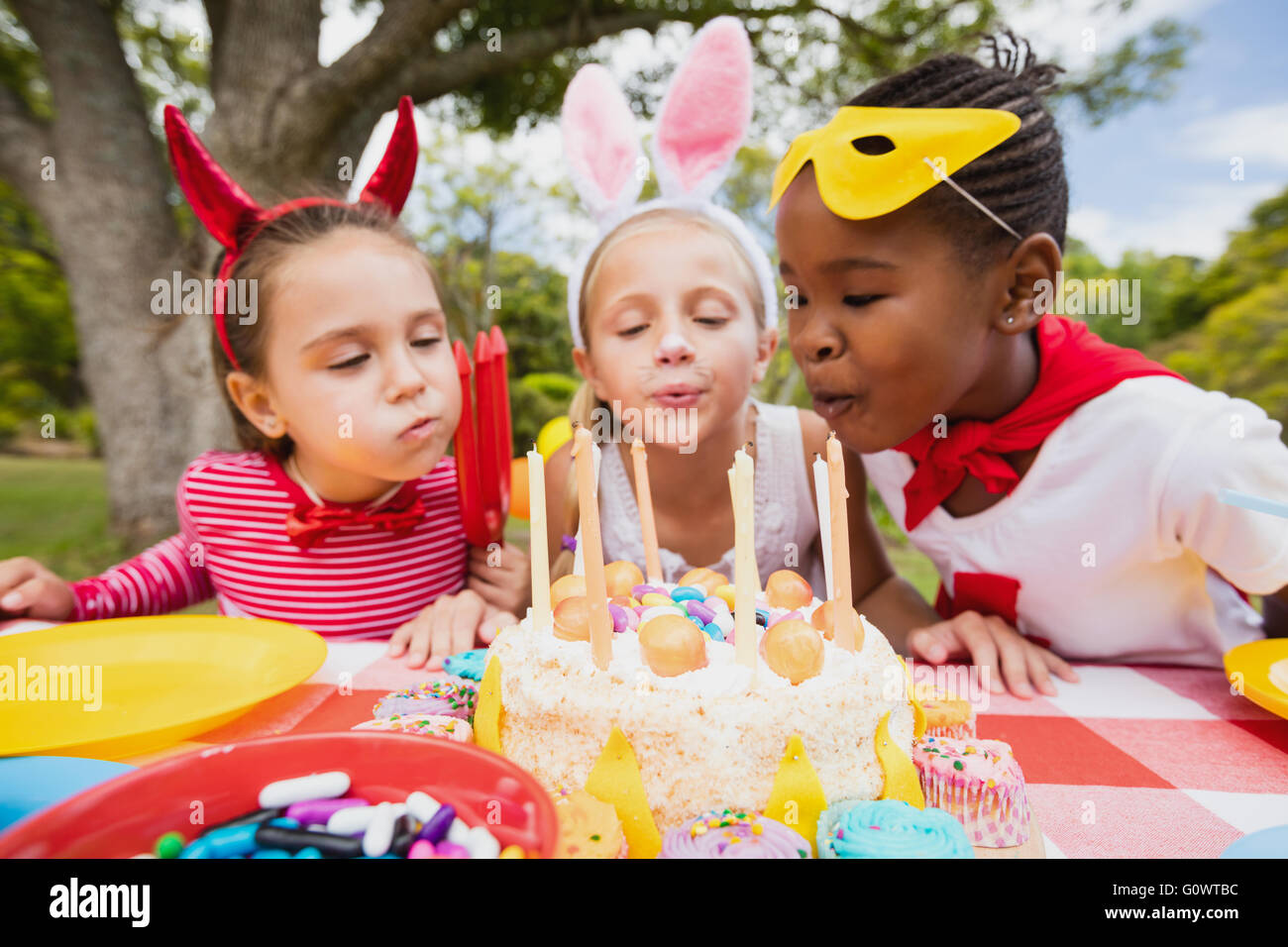 Three little girls blowing together birthday candles Stock Photo