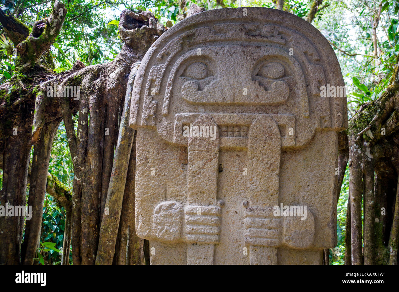 A mysterious statue of a male person stands in the rainforest next to