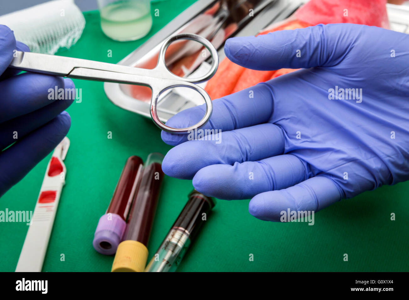 Surgeons hands holding and passing surgical instrument to other doctor while operating patient