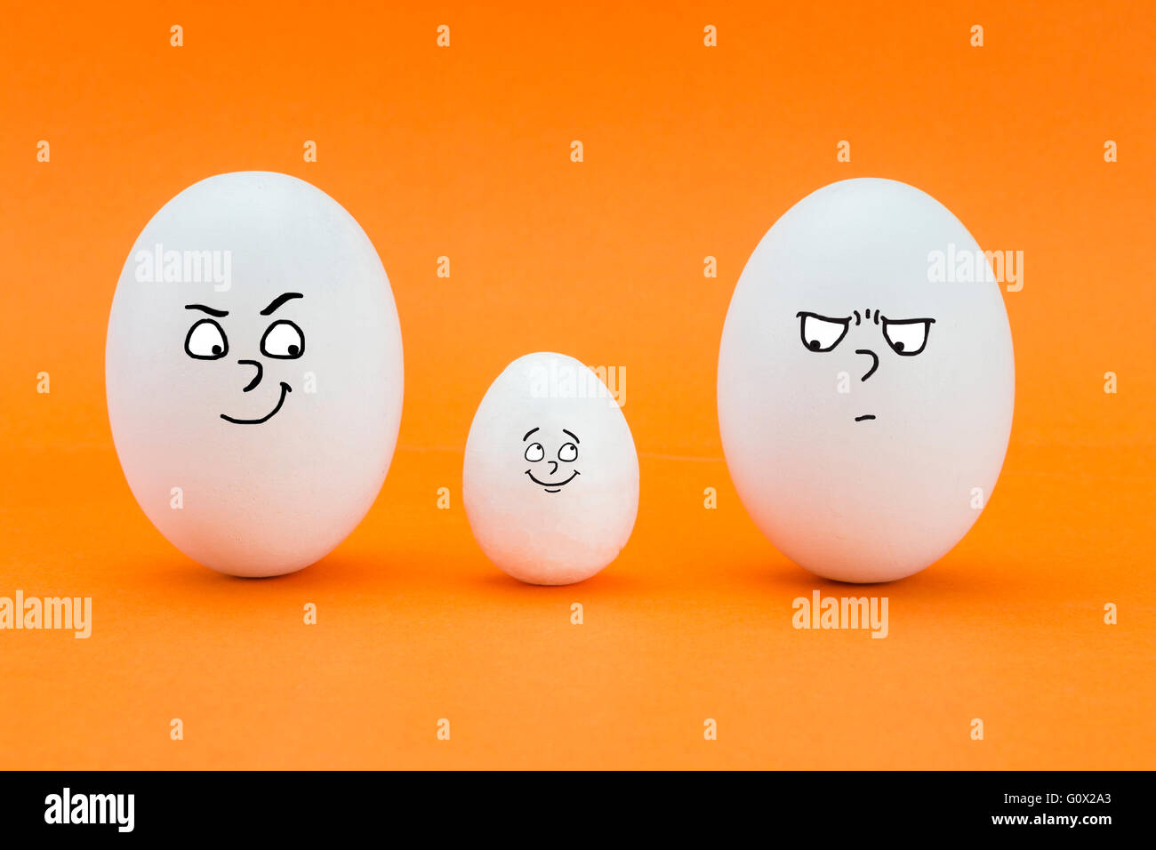 two big eggs look with face of few friends at a small egg isolated on