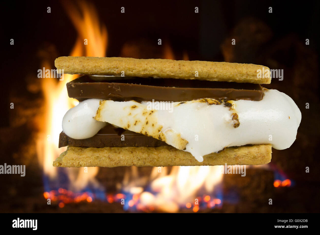 Chocolate s'more made from graham crackers, chocolate bar and melting marshmallow in front of