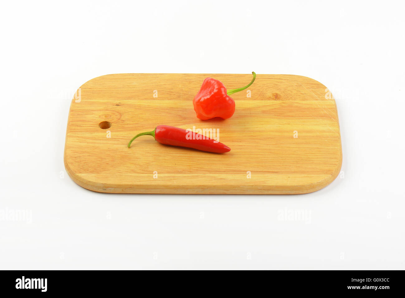 two red hot chili peppers on wooden cutting board Stock Photo - Alamy