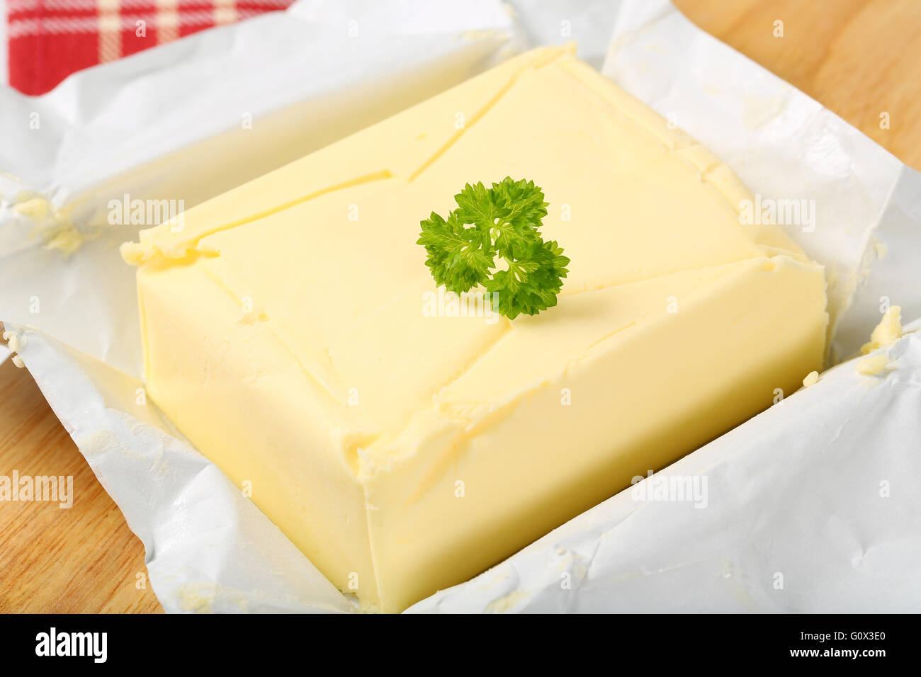 block of fresh butter on wooden cutting board - detail Stock Photo