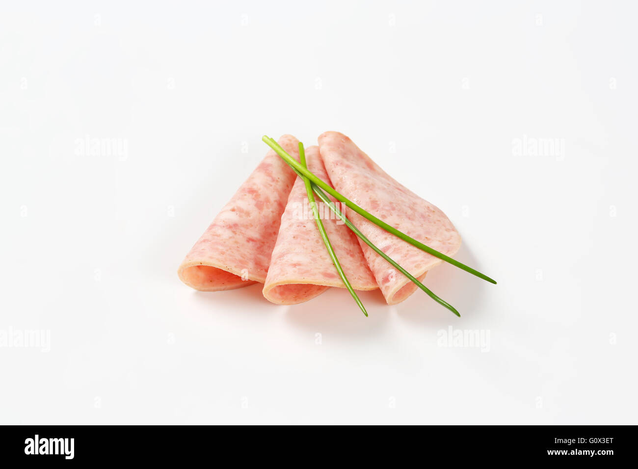 slices of ham salami with chives arranged on white background Stock