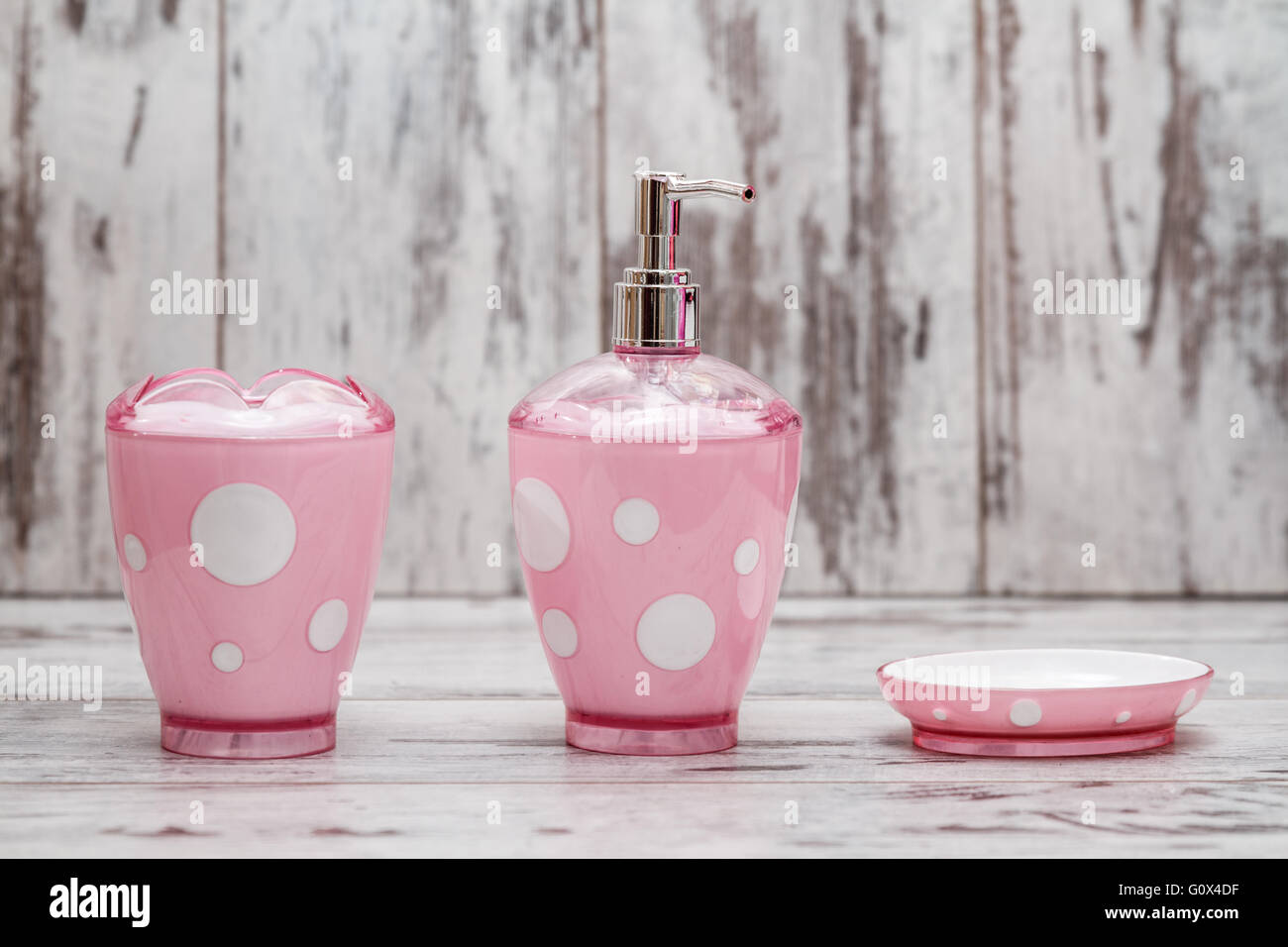 Set of cute pink bathroom accessories on white wooden background Stock