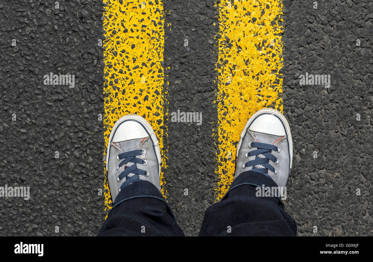 Gray sneaker shoes standing on yellow line. Stock Photo