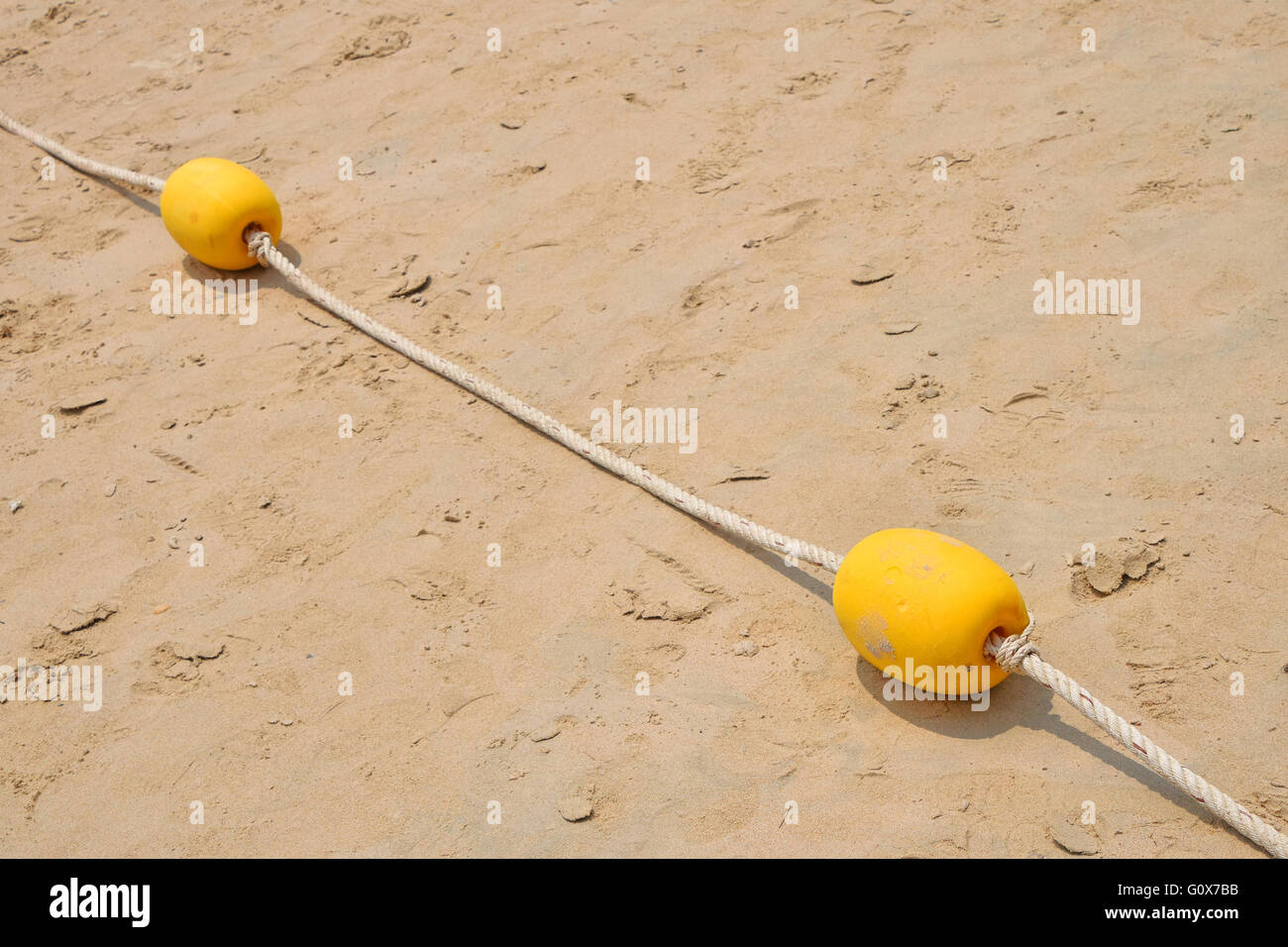 Two yellow polystyrene sea marker buoys with cable tow on wet sand sea beach Stock Photo