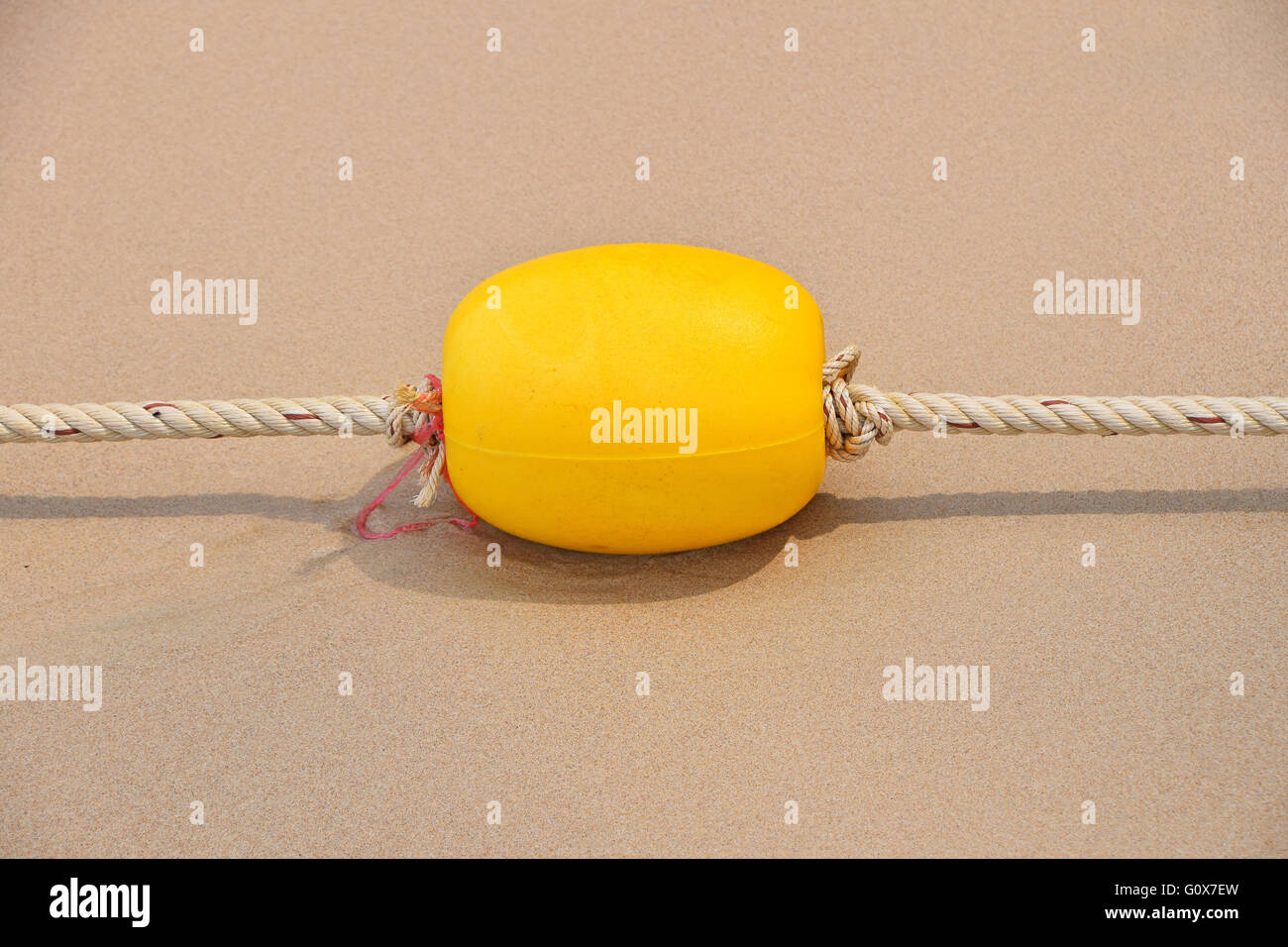 Yellow polystyrene sea marker buoy with cable tow on wet sand sea beach Stock Photo