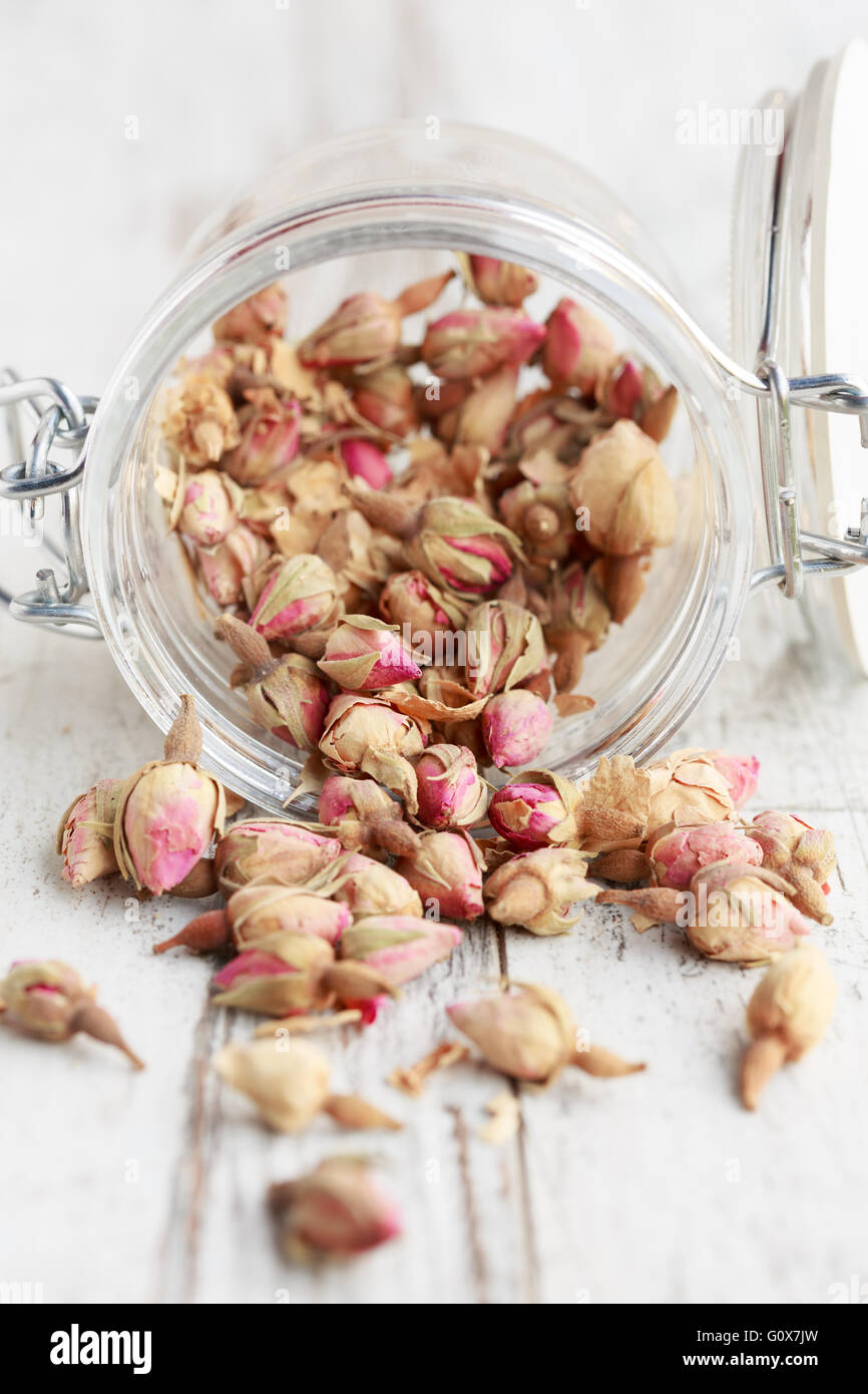 Dried rose buds spilling from a glass jar Stock Photo