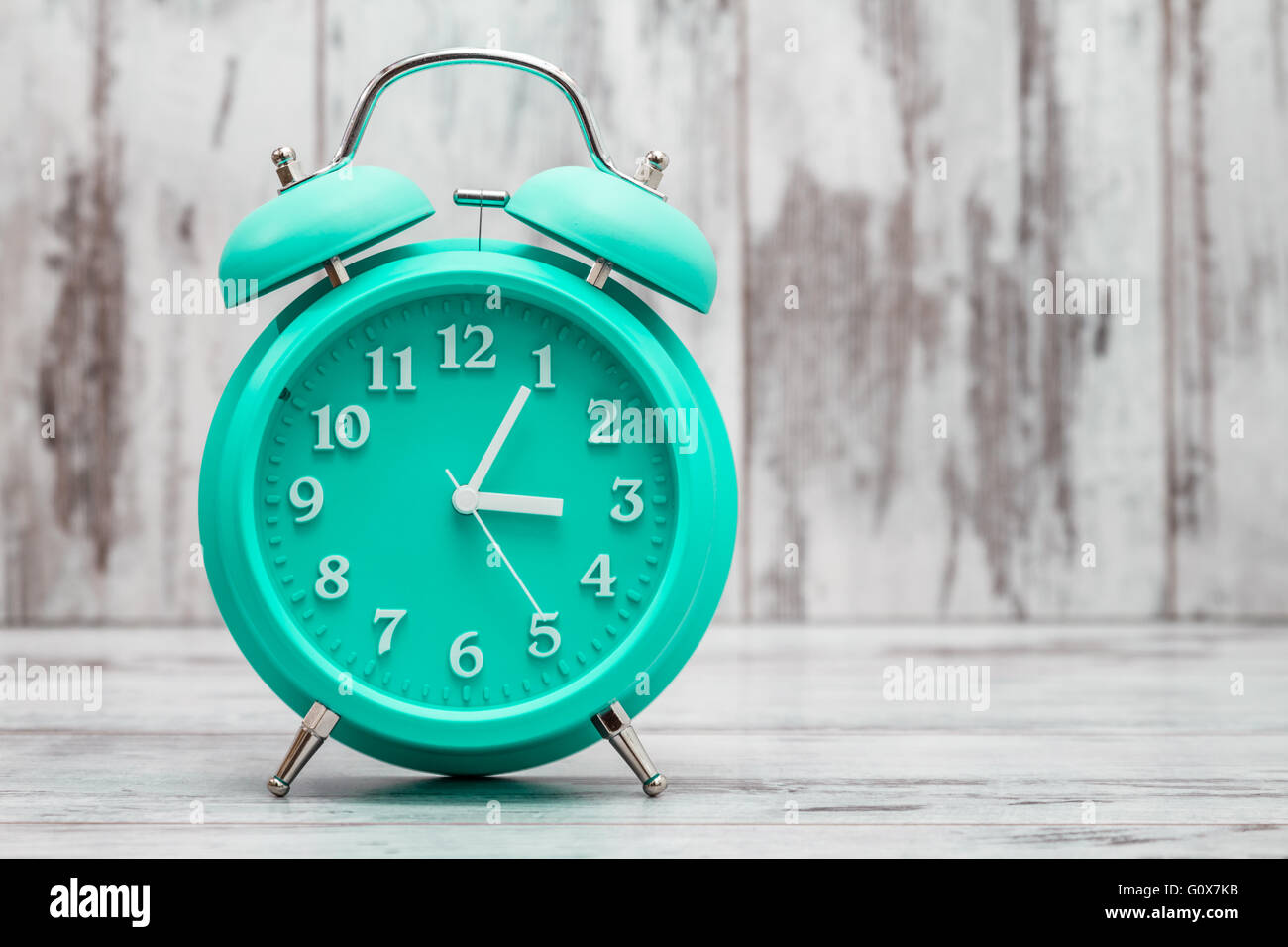 Green retro alarm clock on white wooden background Stock Photo - Alamy